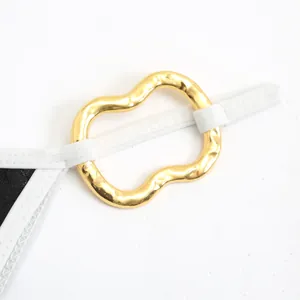 Detailed close-up showing a wavy gold metal ring buckle on a stylish white bikini strap