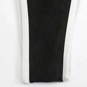 Macro detail of black floral lace fabric and white elastic trim on sexy bikini bottom