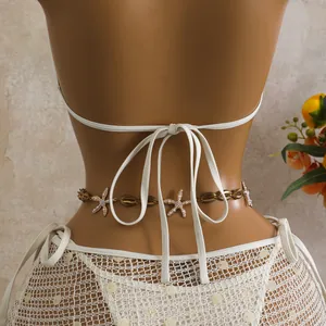 Dettaglio posteriore di bikini in rete bianca con paillettes e catena in vita a stella marina