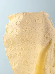 Detailed view of light yellow textured jacquard fabric with floral patterns for swimwear