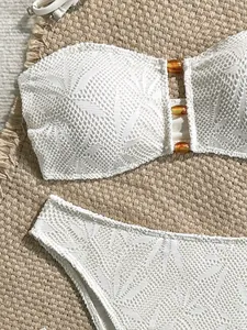 Dettaglio bikini in pizzo bianco con motivi a foglia e perline color ambra