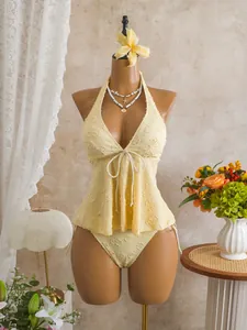 Detailed view of pale yellow textured floral tankini set on mannequin with flower decor.
