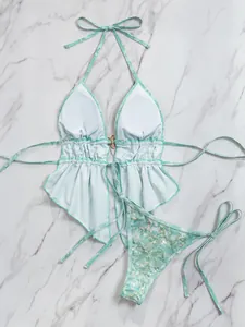 Platte weergave van een bloemige halterbikiniset met lovertjesdetails op marmer.