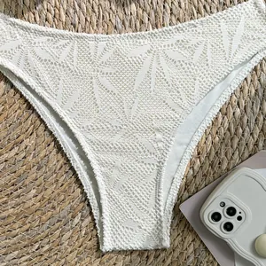 Close-up detail of white crochet lace bikini bottom with intricate geometric hollow-out patterns