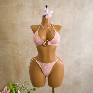 Detailed view of pink smocked bikini with gold ring detail on a mannequin