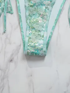 Detailopname van een bloemenbikini met pailletten en 3D-bloemen op groen materiaal