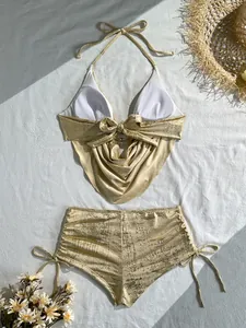 Detailansicht der Textur eines sexy metallisch goldenen Bikini-Badeanzugs mit Wasserfallausschnitt