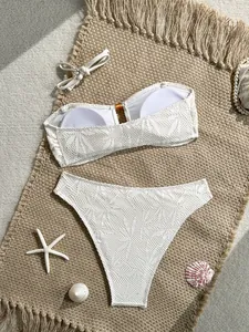 Vista dettagliata del bikini bianco in pizzo a vita alta con accessori da spiaggia