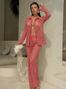 Full view of model in red and white striped resort wear set with a gold shell clutch