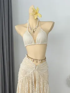 Detail van crème kanten bikini top en bijpassende lange rok met schelpen accessoires