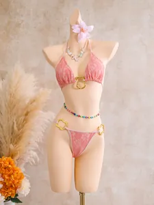 Detail of a pink lace three-piece bikini set featuring gold hardware on a mannequin.