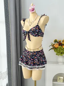 Detail view of floral two-piece swimsuit with ruffled straps and lace-trimmed skirt