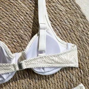 Close-up detail of white lace bikini top with adjustable shoulder strap and metal hardware