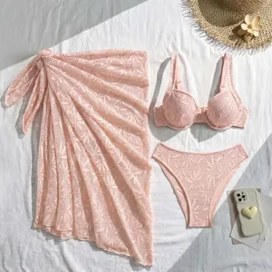 Overhead view of a three-piece pink lace bikini set with matching beach sarong skirt