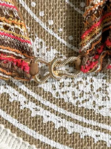 Close-up detail of bohemian striped crochet bikini top featuring a golden knot clasp