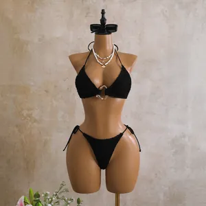 Detailed close-up of textured black bikini top featuring a gold ring on mannequin