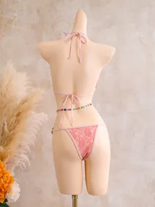 Back view of pink lace bikini with tie-up details and colorful beaded waist chain.