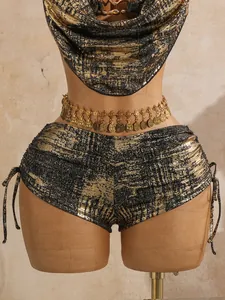 Nahaufnahme eines sexy Bikinis in Goldfolie mit schimmernder Textur und Münzkette