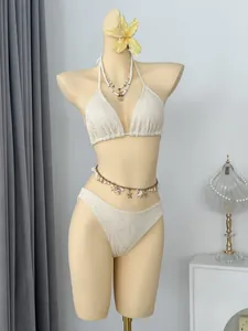 Detailweergave van een witte gehaakte bikiniset op een paspop met decoratieve schelpen