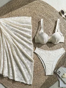 Three-piece white lace bikini set with hollow beach sarong cover-up on straw mat