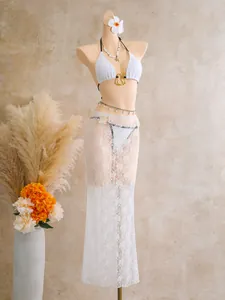 Detailed view of white lace three-piece bikini set with sheer maxi skirt cover-up
