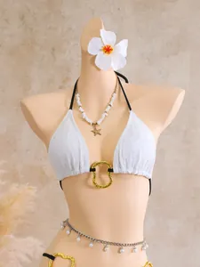 Close-up of white lace halter bikini top with gold ring detail on a mannequin torso