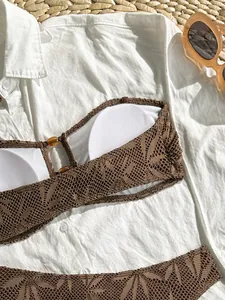 Dettaglio del top bikini in pizzo all'uncinetto marrone con camicia bianca e occhiali.