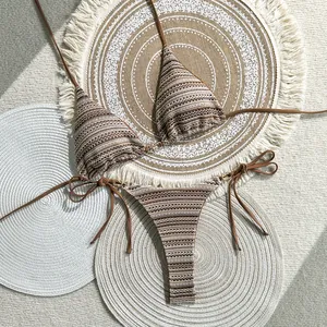 Detail of striped crochet bikini set on woven beach mats with natural sunlight shadows.
