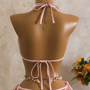 Dettaglio posteriore di bikini rosa in rete con paillettes e catena in vita a stella