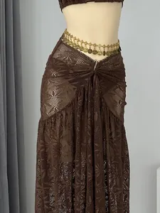 Detailweergave van bruine gehaakte lange rok en goudkleurige tailleketting voor dames.