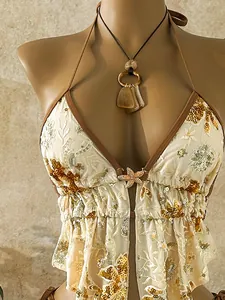 Close-up view of white sequin bikini top with floral embroidery and gold starfish charm