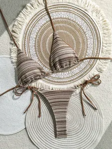 Close-up detail of striped crochet knit bikini set with textured pattern on woven beach mats