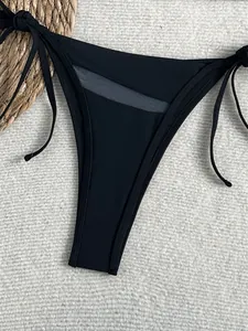 Detailansicht eines schwarzen Bikini-Unterteils mit Netz-Ausschnitt und seitlichen Bändern.