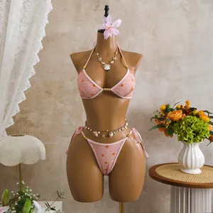 Dettaglio di un bikini rosa con paillettes e accessori con conchiglie e perle