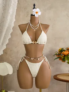 Detailed view of bohemian white lace bikini featuring shell and starfish charms on a mannequin