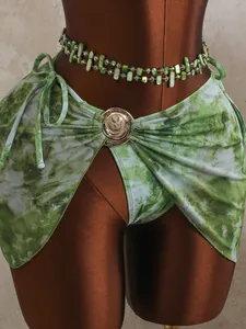 Détail du paréo de bikini en maille tie-dye vert avec boucle dorée et perles.