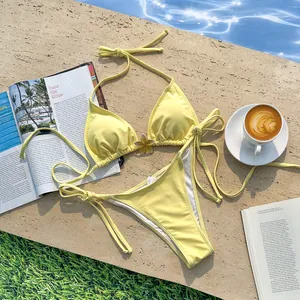 Gele halter bikini set met bloemendetail bij het zwembad met koffie en tijdschrift