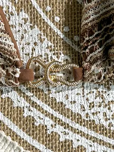 Close-up of gold interlocking metal buckle on striped crochet bikini swimwear detail
