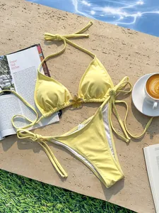 Detailweergave van een gele halterbikini met bloem op een steen bij het zwembad