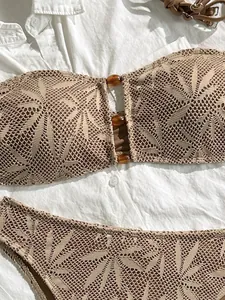Dettaglio bikini all'uncinetto con motivo a foglie e perline marroni su camicia bianca