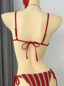 Rückansicht eines roten Bikini-Oberteils und gestreiften Häkel-Slips an einer Schaufensterpuppe