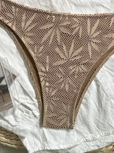 Primo piano di slip bikini a vita alta beige con intricato motivo a foglie all'uncinetto