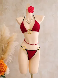 Macro view of the intricate red lace mesh bikini featuring elegant gold metal ring accents