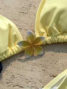 Macro detail van een gele bikini met een decoratieve bloem op een stenen ondergrond