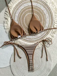 Detailed view of brown striped two-piece bikini set on bohemian woven beach mats.