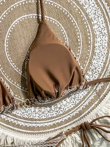 Close-up of brown bikini top with bohemian crochet trim and elegant gold buckle detail