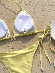 Gedetailleerde weergave van een gele halterbikini met bloemenhanger en gewatteerde voering