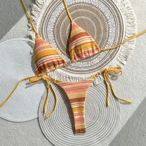 Detailed overhead view of a colorful striped crochet bikini set on rustic woven mats