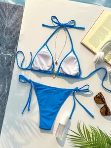 Detail van blauwe halterbikini met gouden bloemornament en strikbroekje