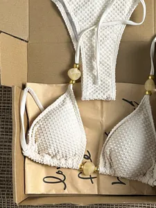 Close-up of white textured bikini top with decorative beads and marble accents